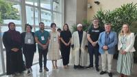 Representantes de povos migrantes, da ONU e da Ufes posam no hall de entrada do Labpetro. 