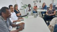 Foto do pró-reitor Antônio Carlos Moraes e do diretor Iury Pessôa sentados à mesa diante da equipe do RU.