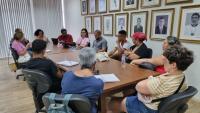 Foto da sala de reuniões da Reitoria, com todos os participantes em reunião, sentados em volta da mesa