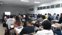 Sala de aula cheia com estudantes e professor ao fundo
