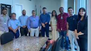 Reunião na SPU Foto da reunião na sala da SPU, com todos os presentes em pé, envolta da mesa.