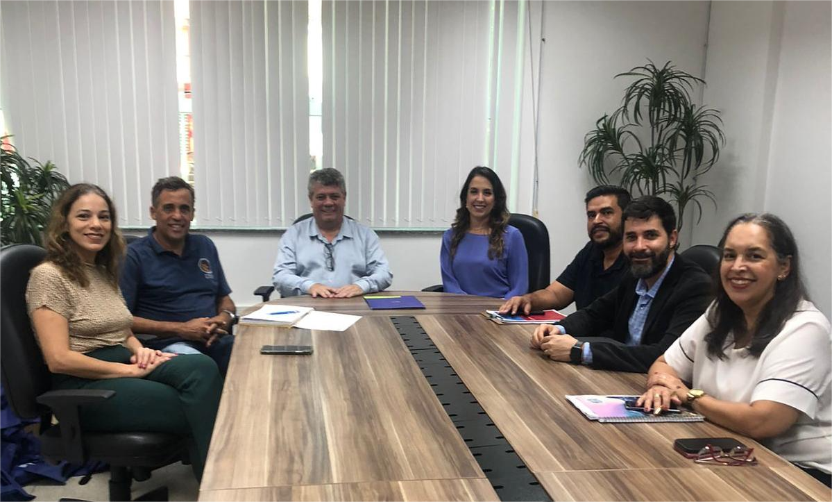 Na foto, os participantes da reunião sentados em volta da mesa.