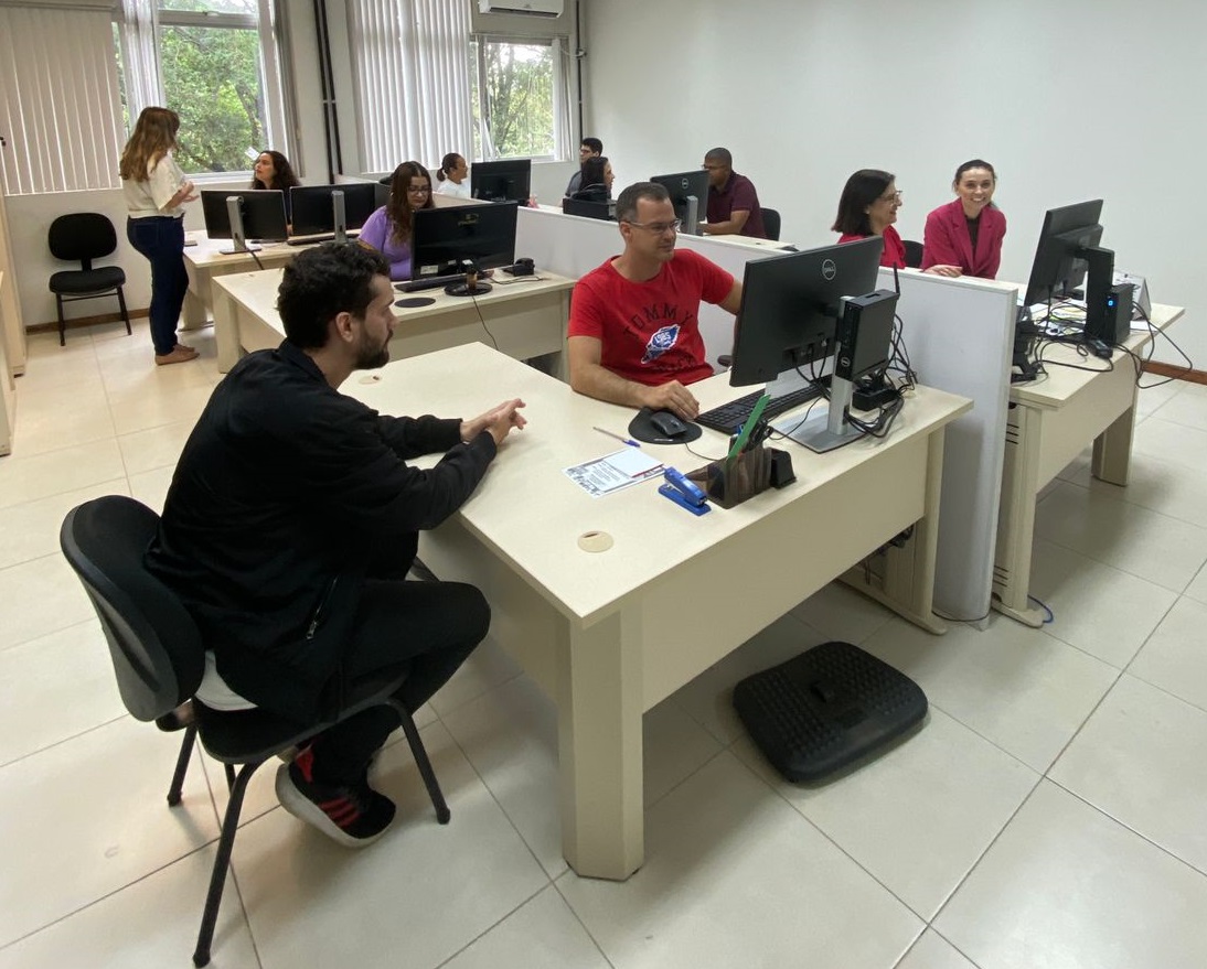 Foto de servidores trabalhando e atendendo pessoas em suas estações de trabalho