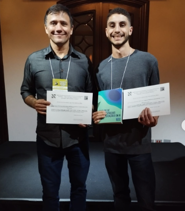 Foto de Emerson Pazeto e Rafael Herzog, ambos segurando o certificado da premiação. 