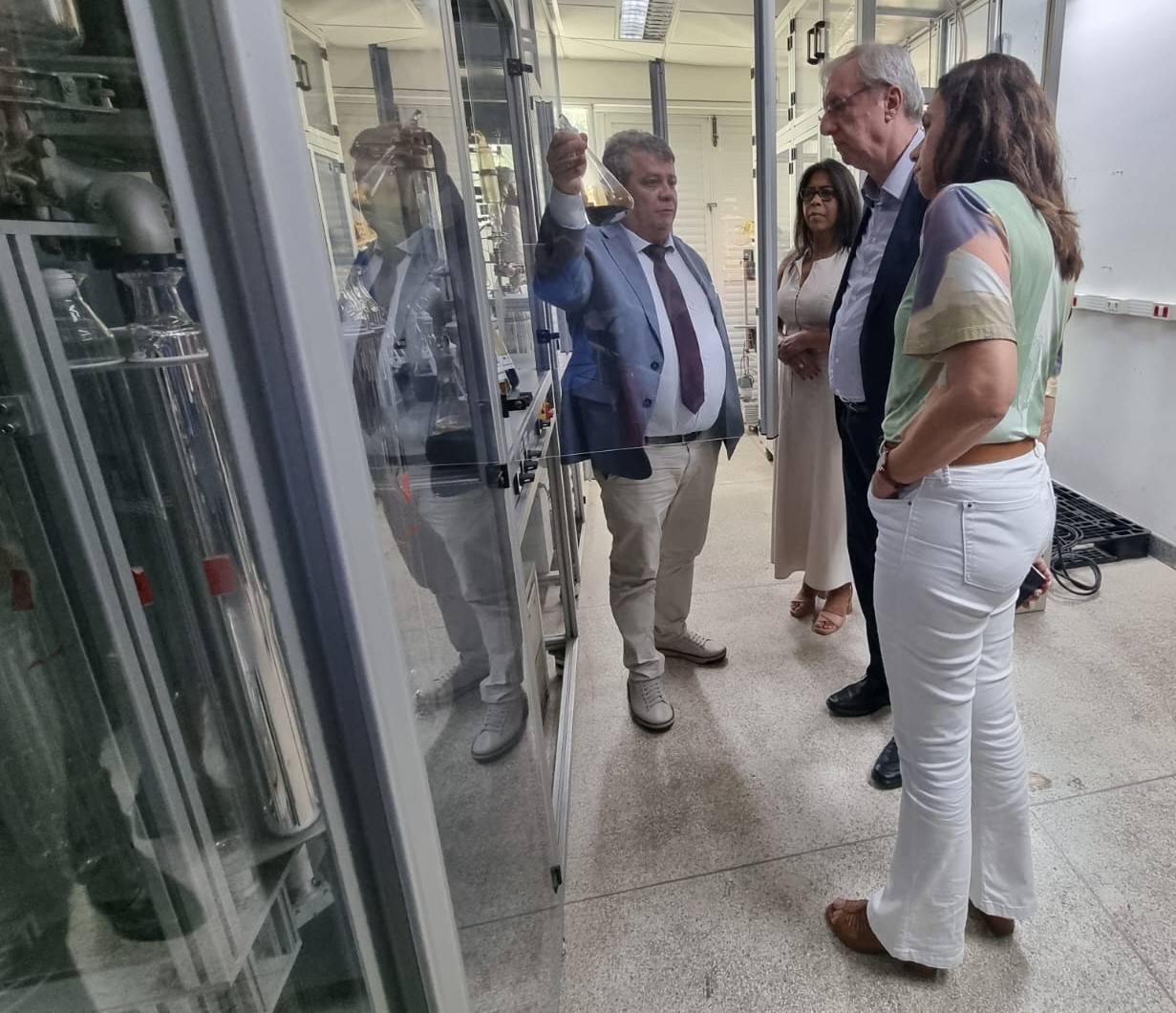 Foto do reitor Eustaquio de Castro apresentando uma amostra de petróleo ao presidente da Finep. Na foto também estão a vice-reitora e a superintendente de Projetos e Inovação