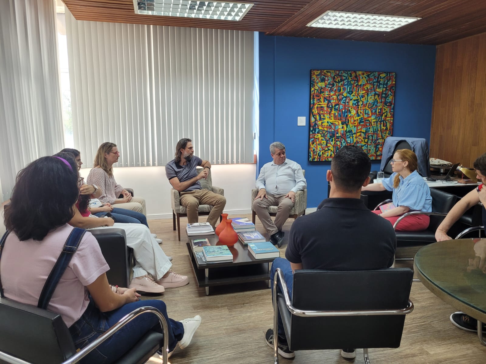 Foto da reunião, com todos os participantes sentados no gabinete do reitor