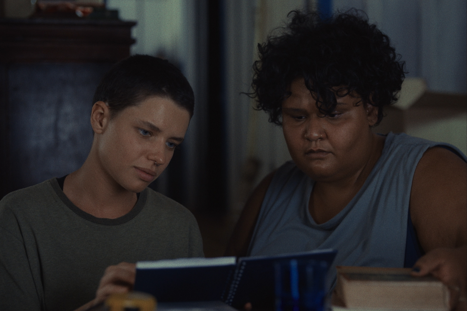 Cena de Cidade; Campo, na qual duas mulheres estão olhando para um caderno