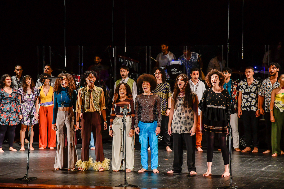 Foto do Coral Jovem Vale Música em uma apresentação, com os integrantes usando  roupas coloridas.