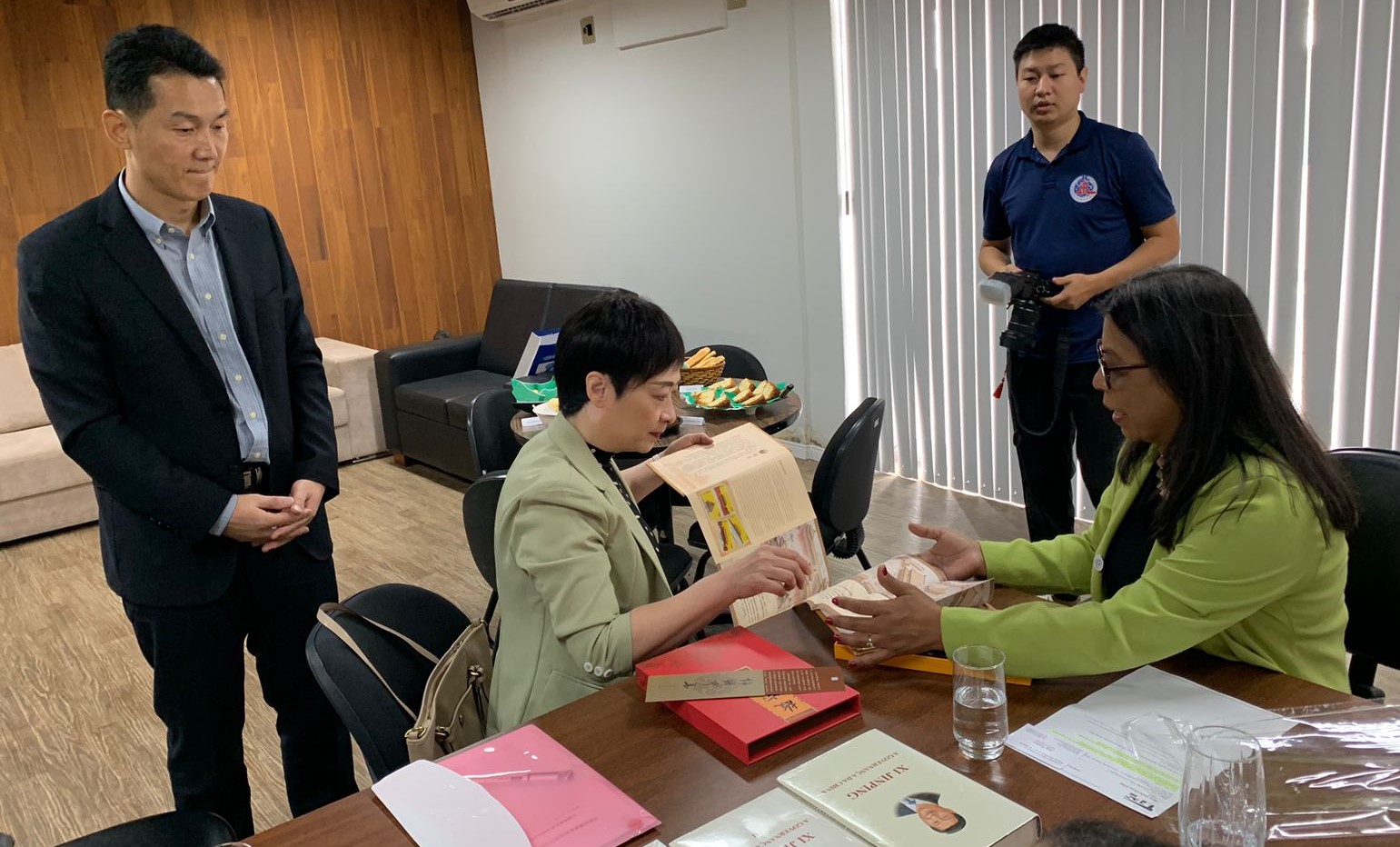 Visita do Consulado Chinês à Ufes Foto da consulesa geral da China mostrando um livro para a vice-reitora da Ufes