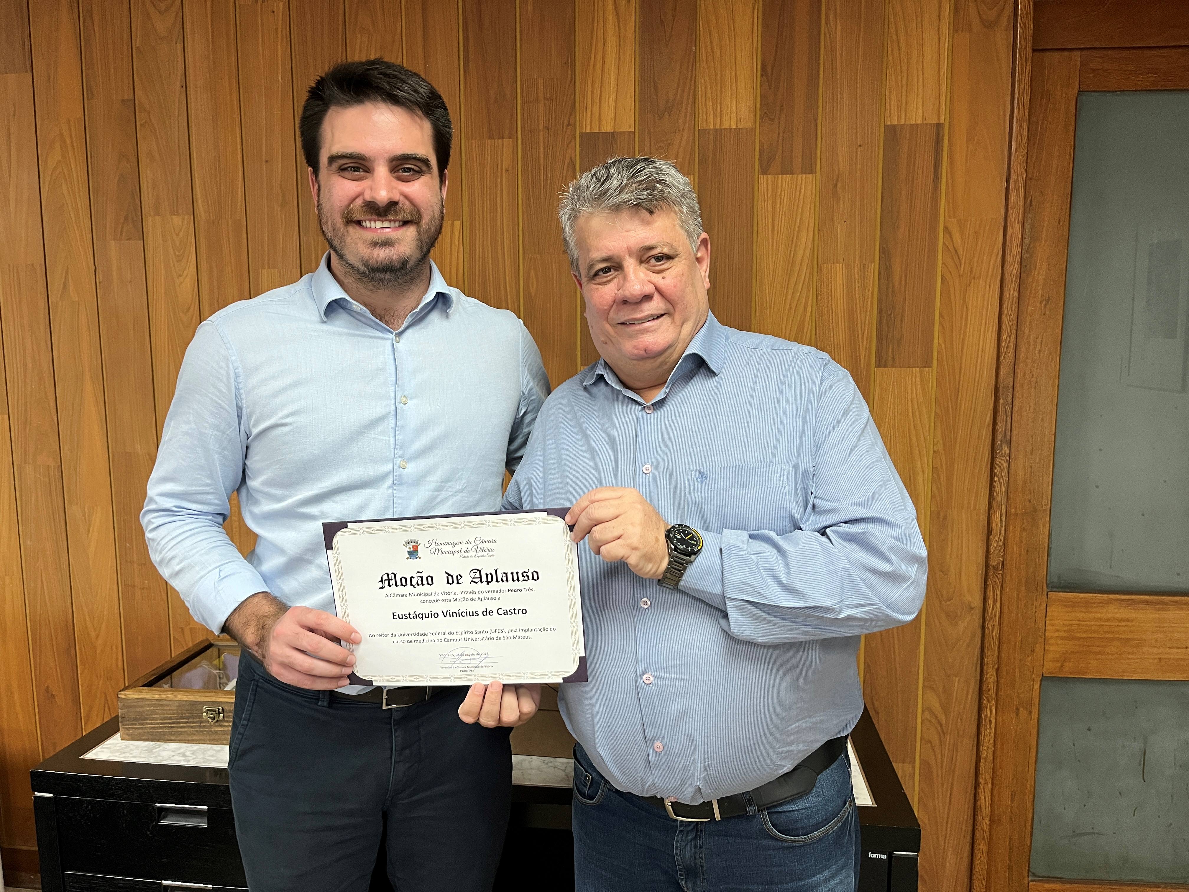 Foto do vereador Pedro Trés ao lado do reitor, ambos segurando o diploma da moção