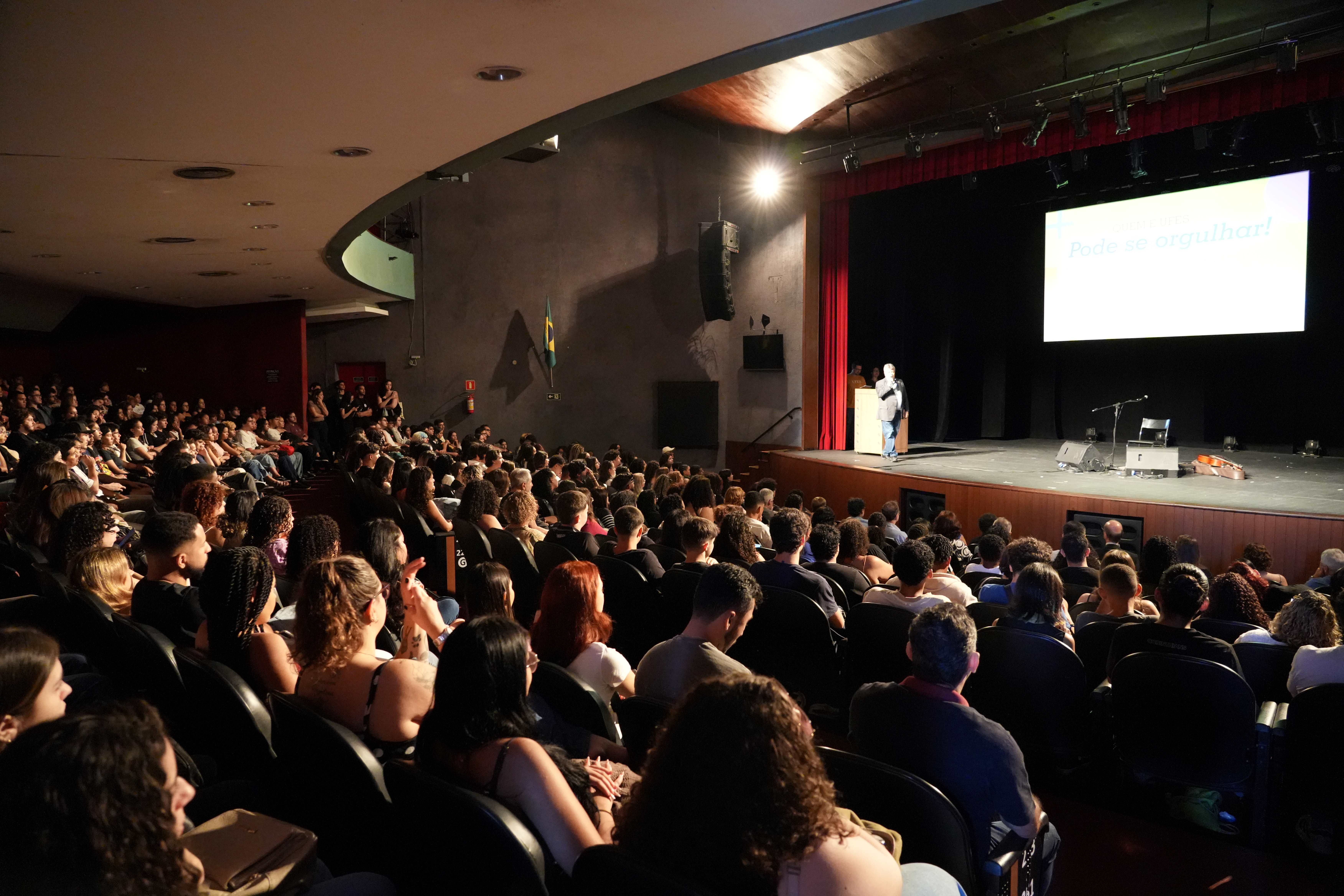 Foto do reitor falando para os estudantes no teatro