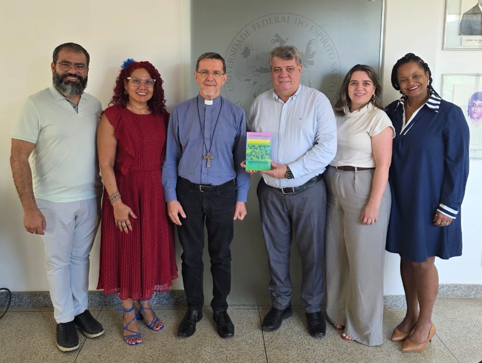 Foto dos participantes do encontro, com o reitor segurando o livro