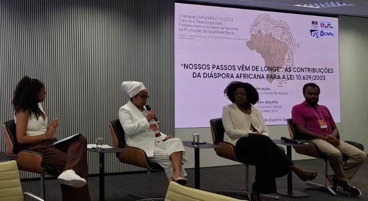 Foto da professora Débora apresentando à pesquisa, sentada ao lado de outras três pessoas