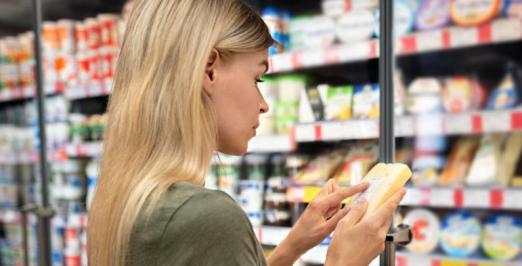 Foto de uma mulher olhando o rótulo de um alimento no supermercado