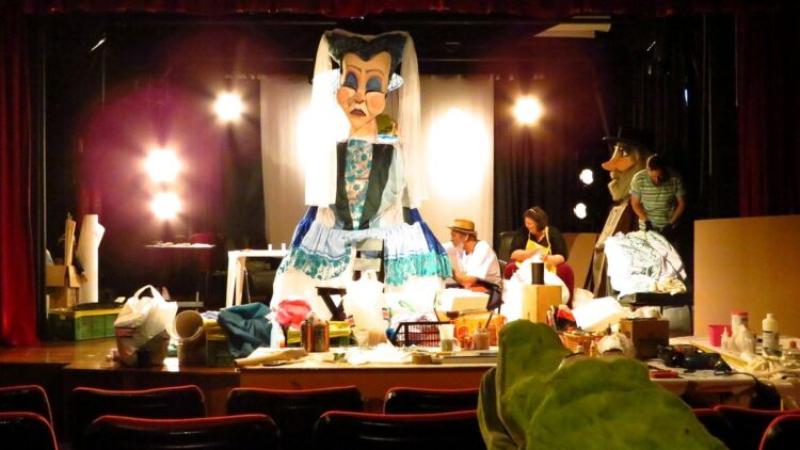 Cena de Os 80 Gigantes, onde há vários elementos cênicos sobre um palco de teatro