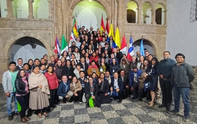 Foto dos participantes do evento em uma escadaria, com bandeiras dos países participantes