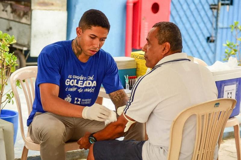 Foto de um jovem aferindo a pressão de um senhor na ação de 2024