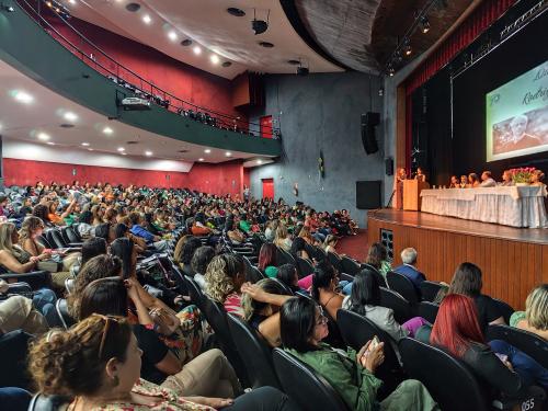 Foto da parte interna do teatro universitário, mostrando o grande público presente. A fundo, a mesa de abertura.