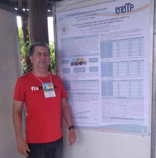 Foto do professor Robson de Sousa à frente do banner da pesquisa apresentada 
