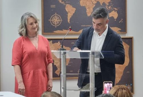 Foto do diretor assinando o termo de posse. Ao seu lado, a vice-diretora eleita