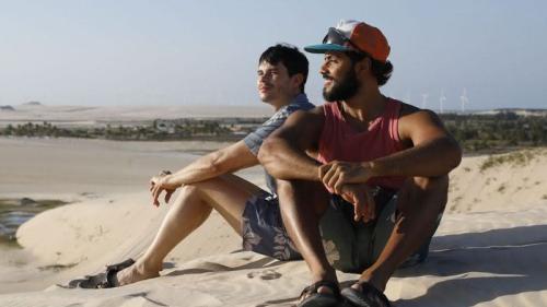 Cena de O Melhor Amigo, na qual os dois personagens aparecem sentados na areia 