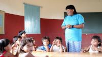 Crianças indígenas em uma sala de aula, com um professor indígena