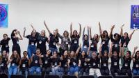 Foto dos integrantes da liga reunidos, todos vestindo camisas pretas e com os braços para cima, em comemoração