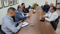 Foto da reunião, com os participantes sentados em volta da mesa.