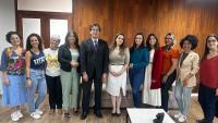 Foto das equipes da Siac e da Defensoria Pública, com a pessoas posando, em pé, na sala de reuniões da Reitoria.