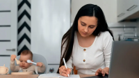 Imagem de uma mãe estudando, tendo ao lado um notebook e um bebê sentado em uma cadeirinha