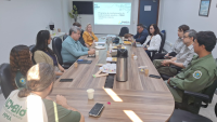 Foto da reunião, com os participantes conversando em volta de uma grande mesa