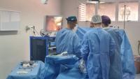 Foto de três médicos em um centro cirúrgico realizando uma cirurgia