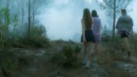 Cena de Ovnis, Monstros e Utopias, na qual aparecem duas mulheres e um homem de costas, andando em uma floresta com denso nevoeiro