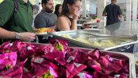 Foto de estudantes se servindo de sobremesa no restaurante, com foco em uma bandeja de bombons