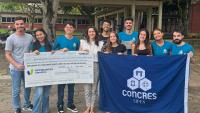 Foto dos estudantes segurando o cheque do prêmio e uma bandeira com o nome do projeto de extensão