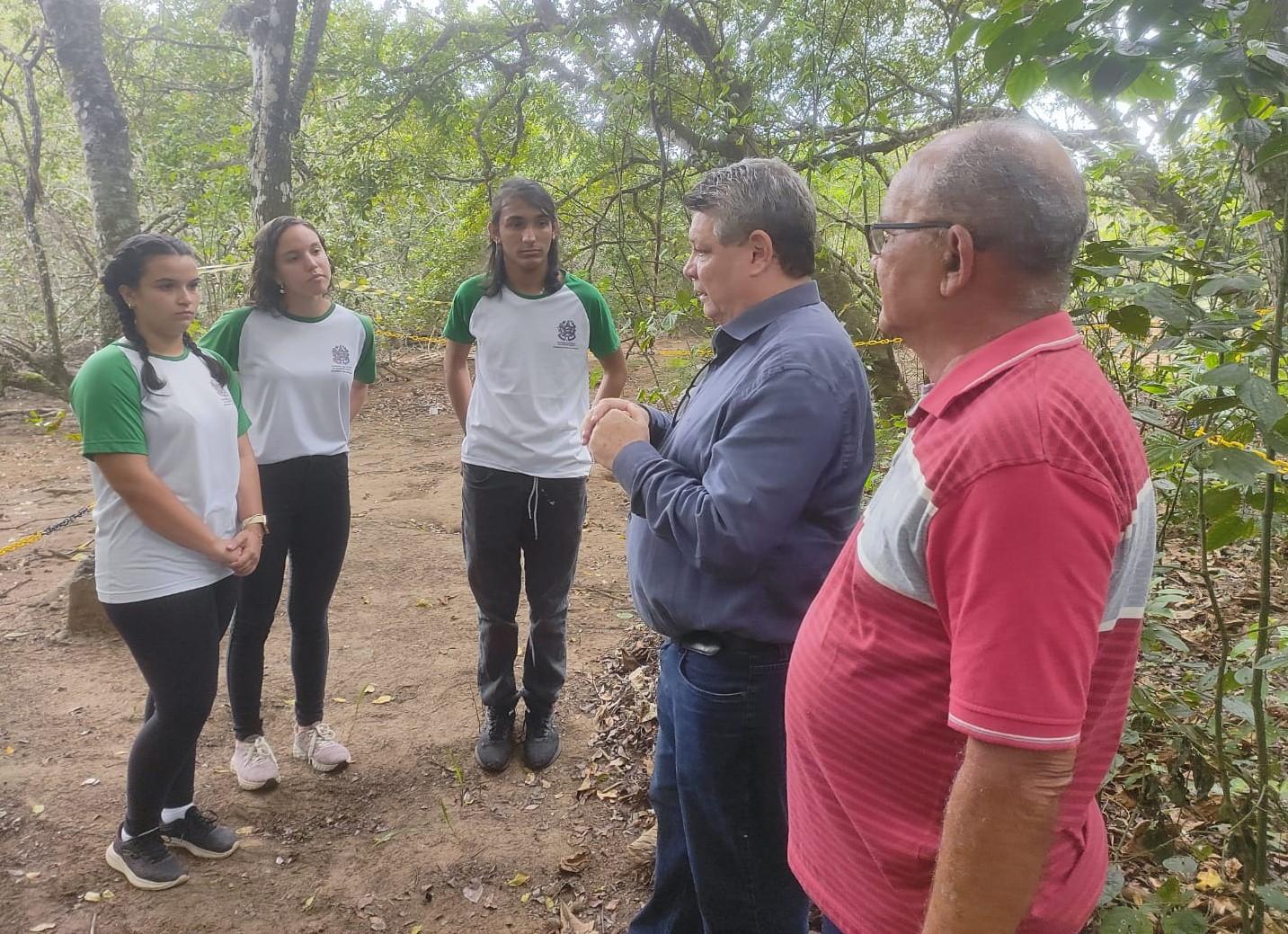 Foto do reitor da Ufes na área do manguezal falando para três estudantes. Na foto também aparece um senhor de camisa vermelha.