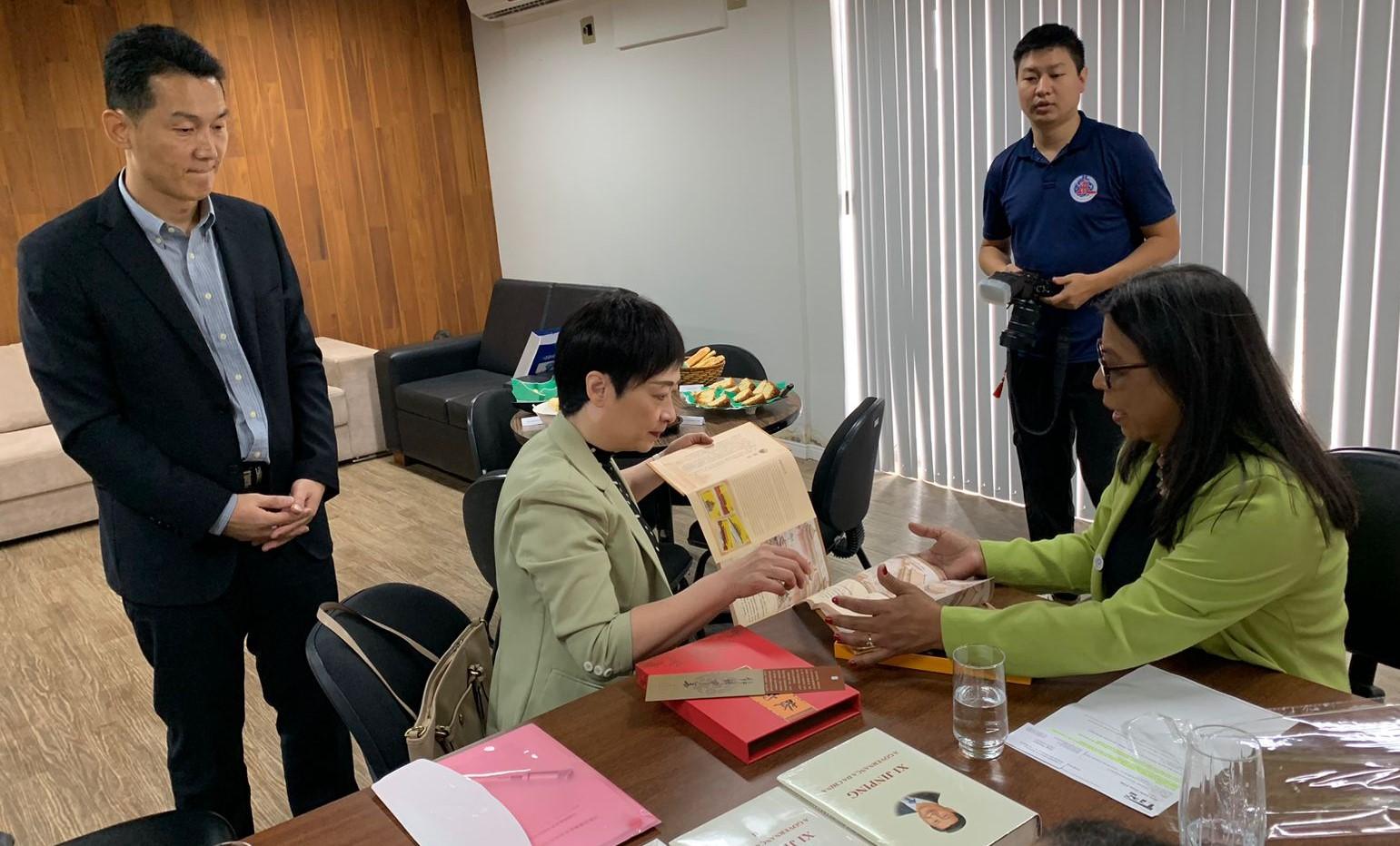 Foto da consulesa geral da China mostrando um livro para a vice-reitora da Ufes