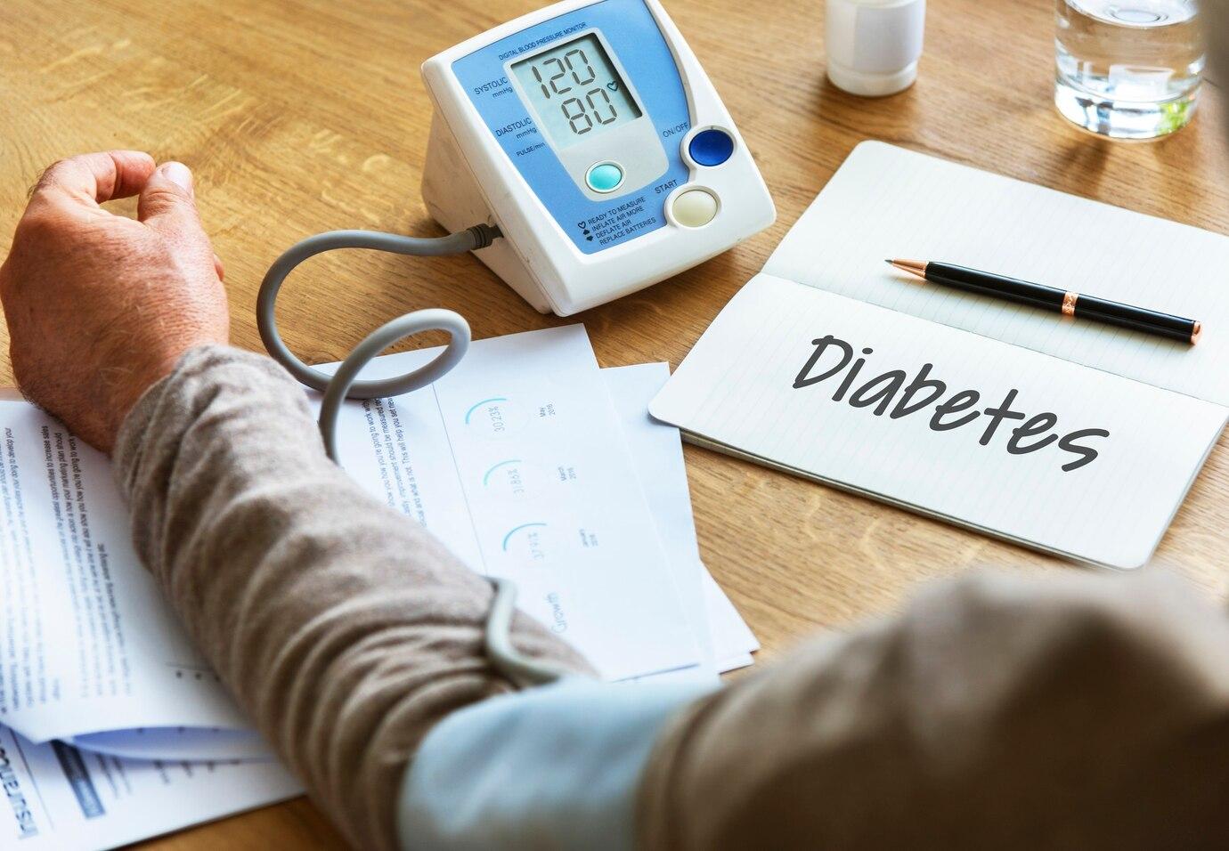 Imagem do braço de um paciente com aparelho de medir pressão arterial. Ao lado, um bloco onde se lê "diabetes"