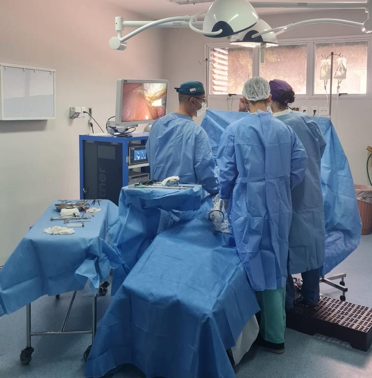 Foto de três médicos em um centro cirúrgico realizando uma cirurgia