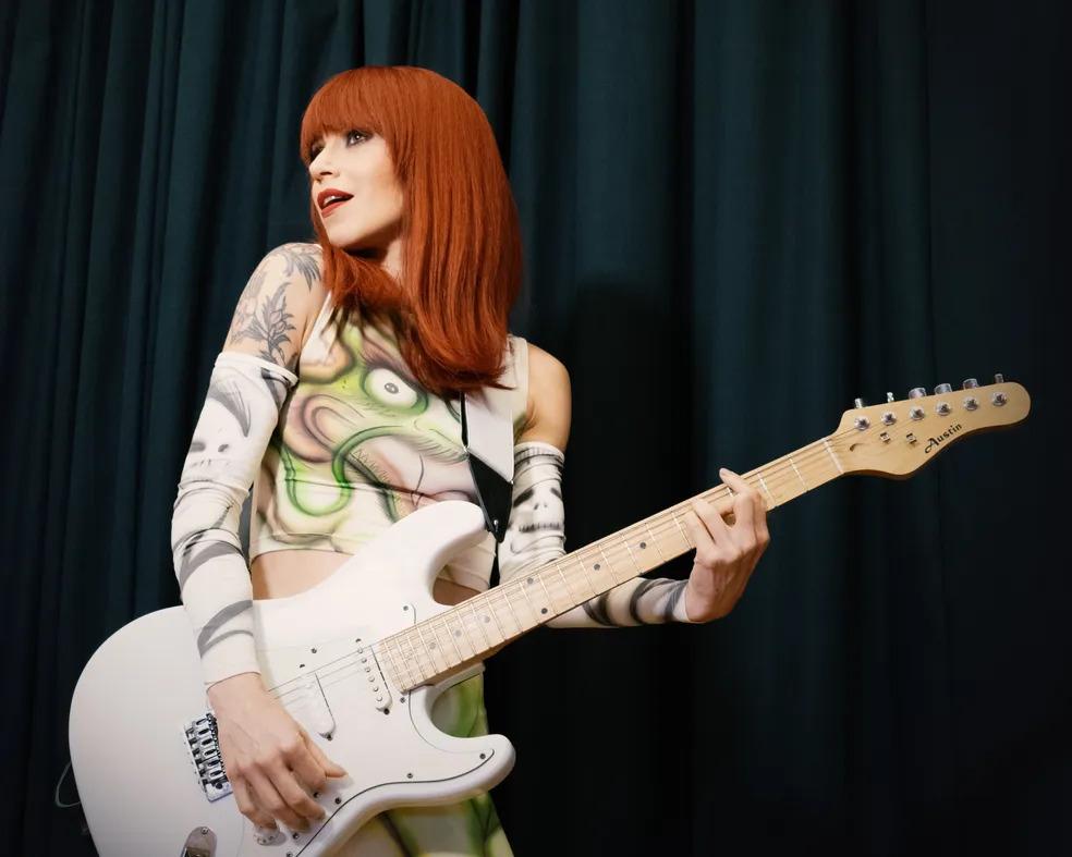 Foto da atriz Mel Lisboa segurando uma guitarra em uma cena do espetáculo