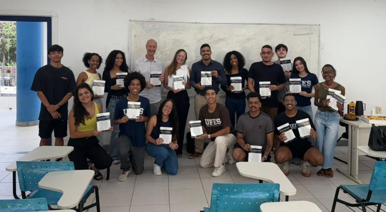 Foto dos estudantes e do professor com o livro na mão
