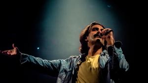 Foto do ator Pablo Paleólogo cantando caracterizado como Belchior