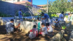 Foto de crianças e monitores pintando as paredes dos canteiros. 