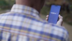 Foto de um homem de costas segurando um celular e, na tela, o nome HidroES