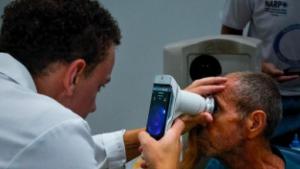 Foto de um médico utilizando um retinógrafo portátil para examinar uma paciente