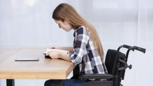 A Ufes atende hoje 522 alunos com deficiência Mulher cadeirante escrevendo à mesa
