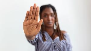 Imagem de uma mulher negra com a mão espalmada indicando "pare"