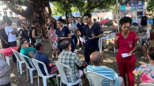 Grupo de estudantes atendendo várias pessoas sentadas em cadeiras