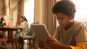 Imagem de um adolescente negro olhando a tela de um tablet