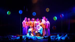 Orquestra Brasileira de Cantores Cegos Cena de uma das apresentações, com os cantores reunidos no centro do palco, decorado com balões
